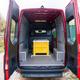 a view of the rear cargo area in a 2023 mercedes benz sprinter awd cargo van. the van is red, with both rear cargo doors open. a large yellow bin sits inside the van.